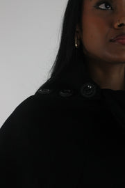 detail view of black button-detail asymmetric poncho