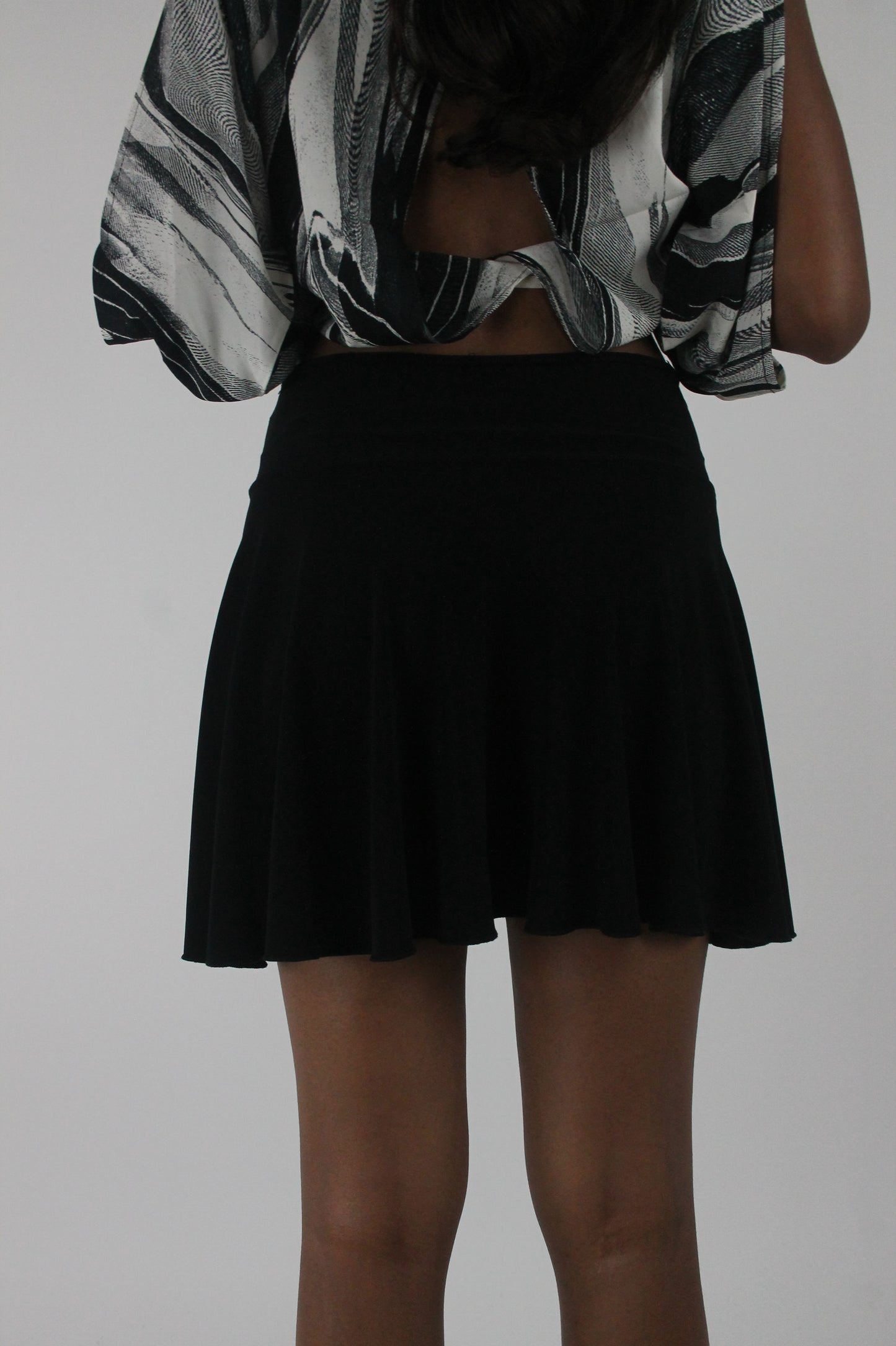 back view of black flared eyelet-waist mini skirt