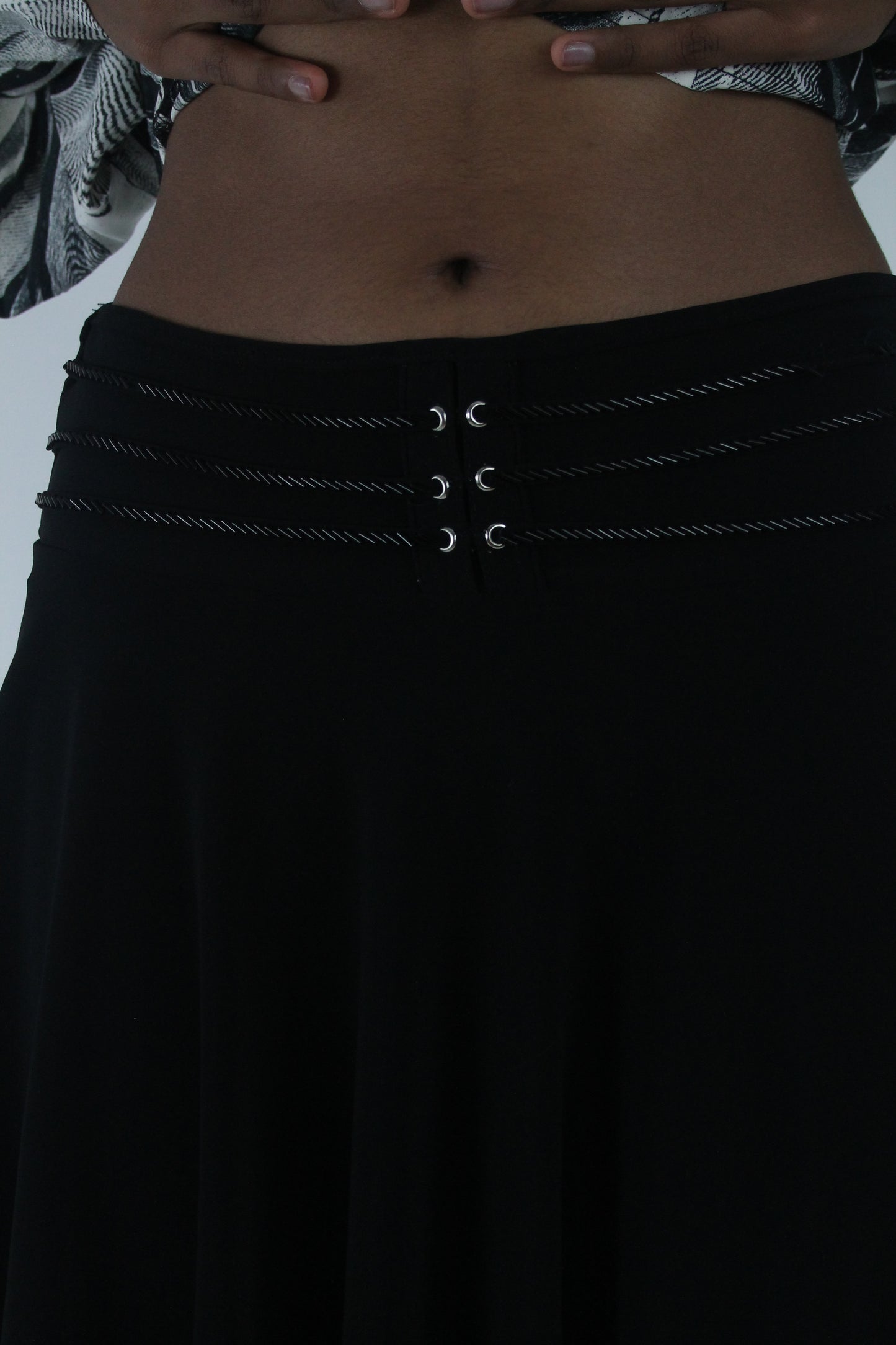 detail view of black flared eyelet-waist mini skirt