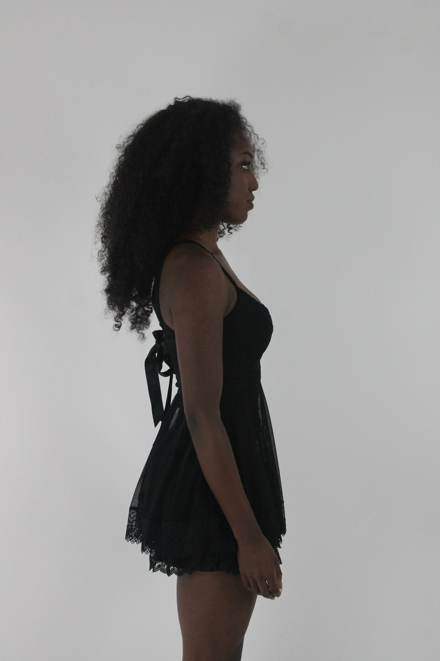 alternate-side view of black lace-trim babydoll mini dress