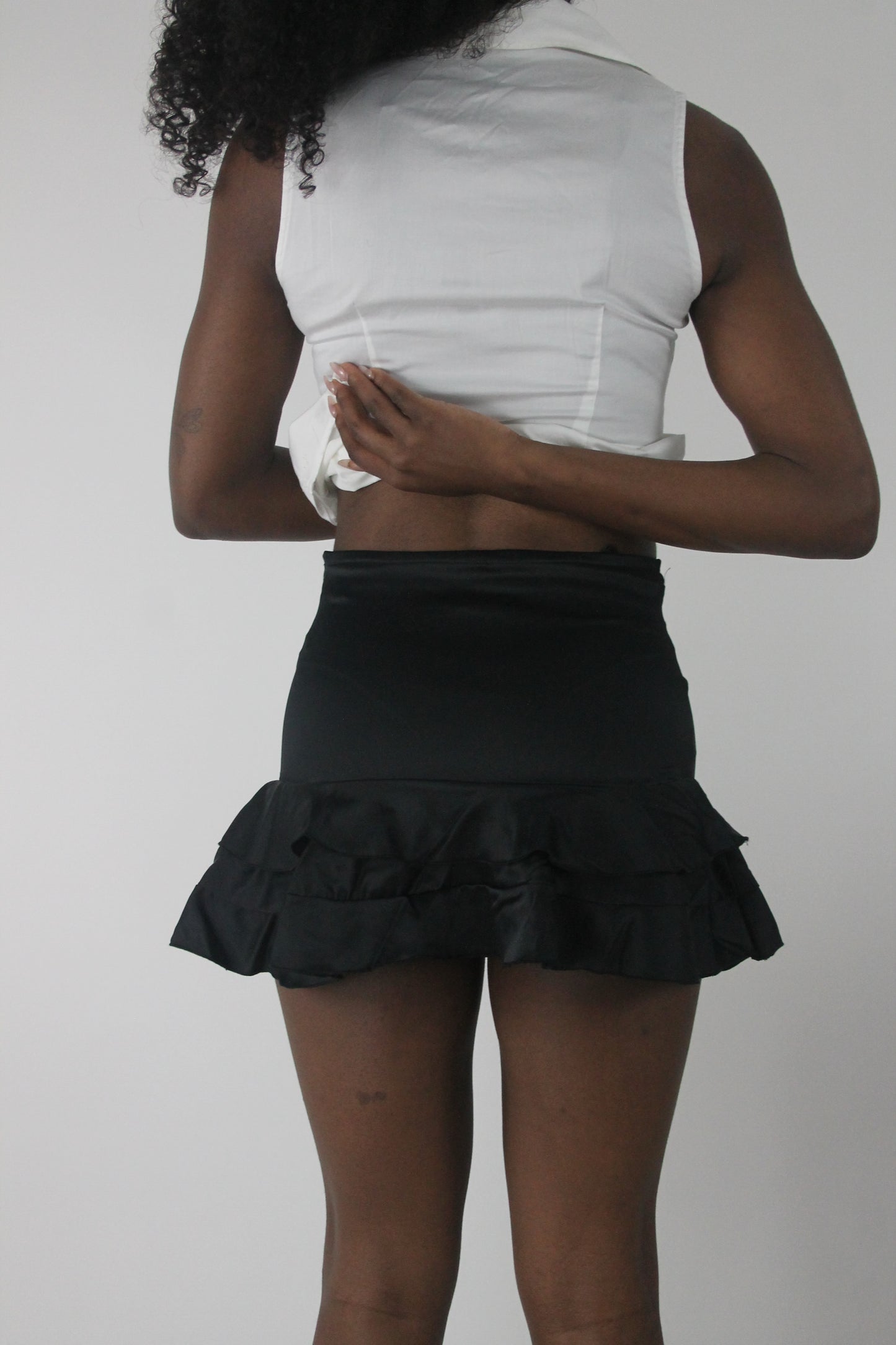 back view of black lace-up ruffle mini skirt
