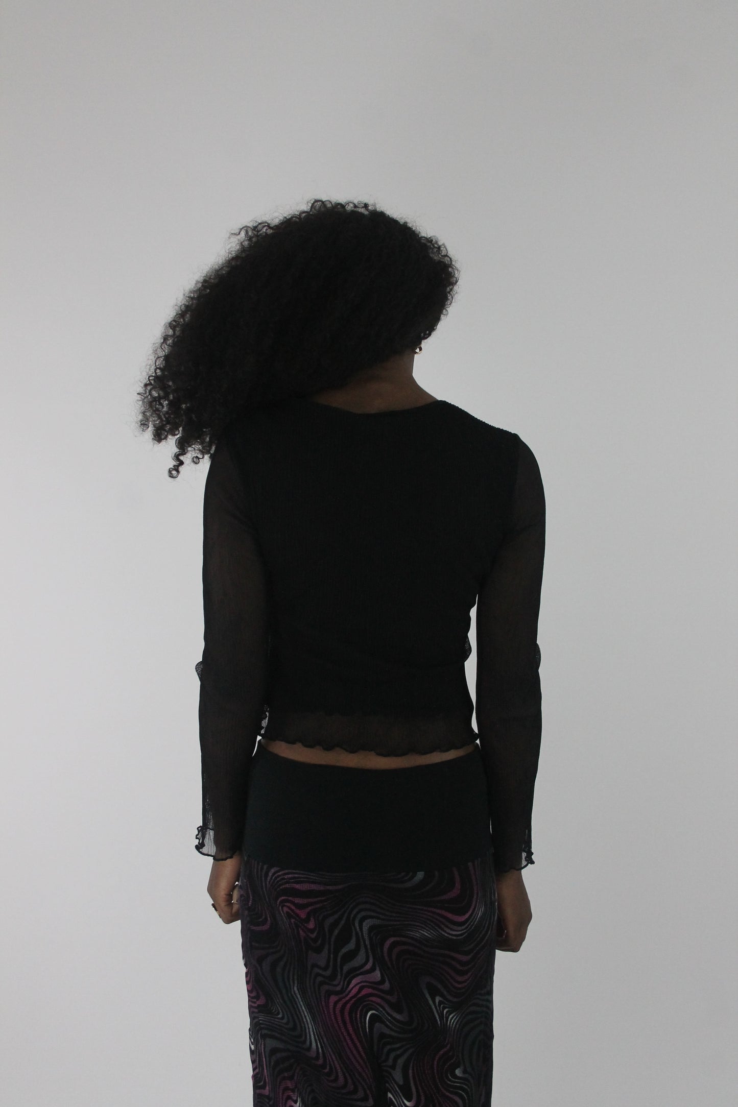 back view of black mesh ruffle-hem long-sleeve top