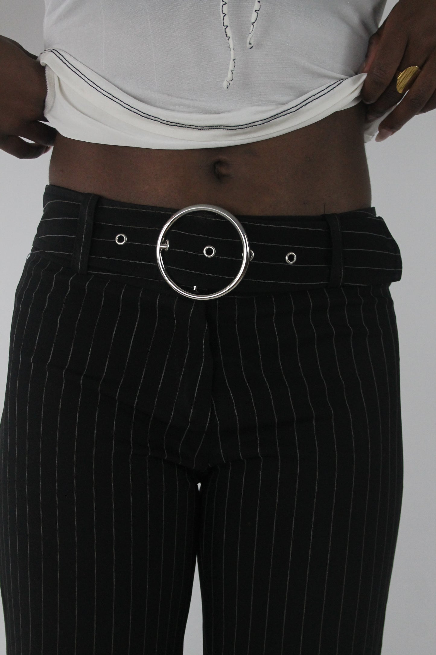 detail view of black pinstripe buckle-belt flared trousers