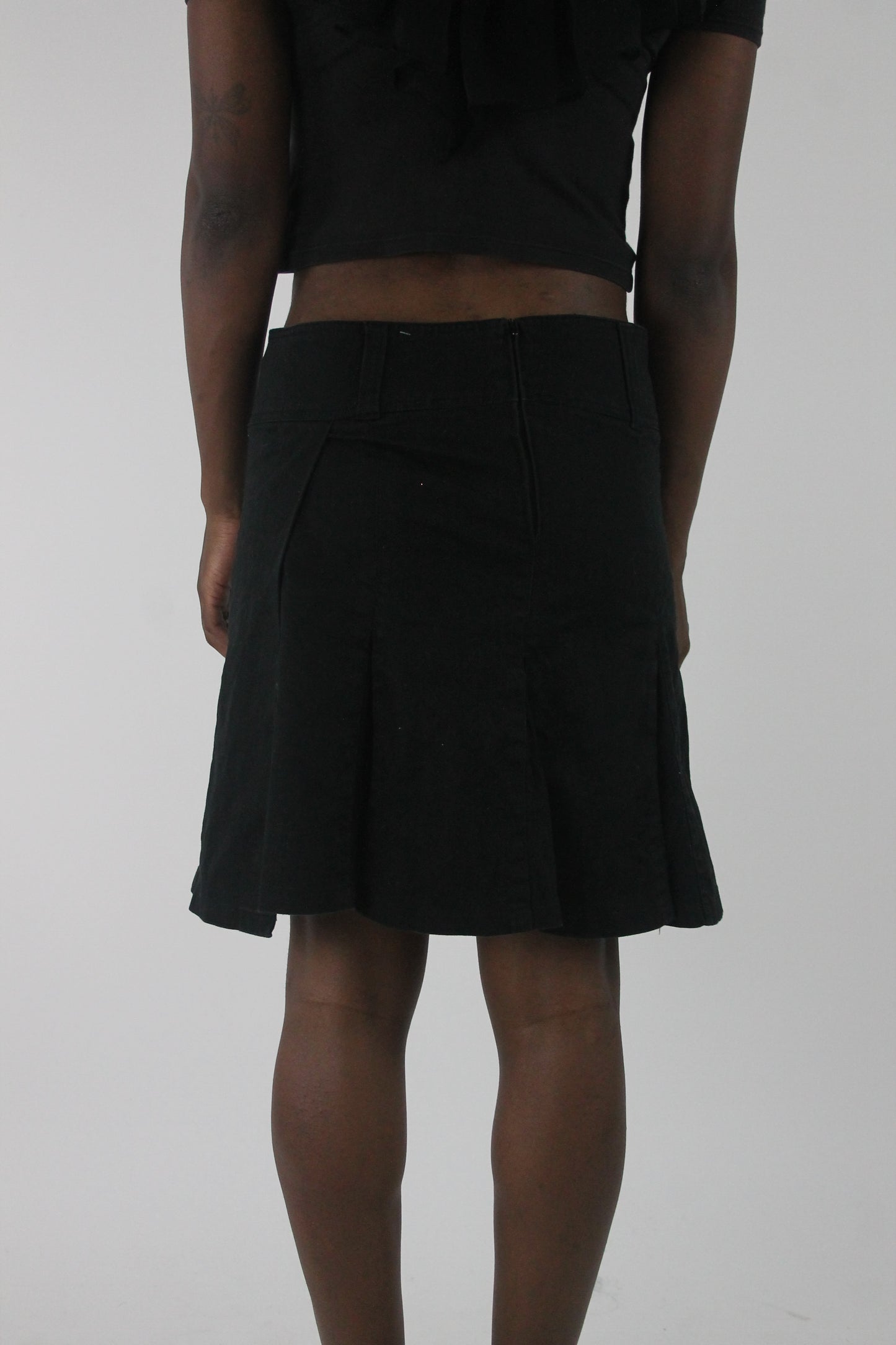 back view of black pleated mini skirt