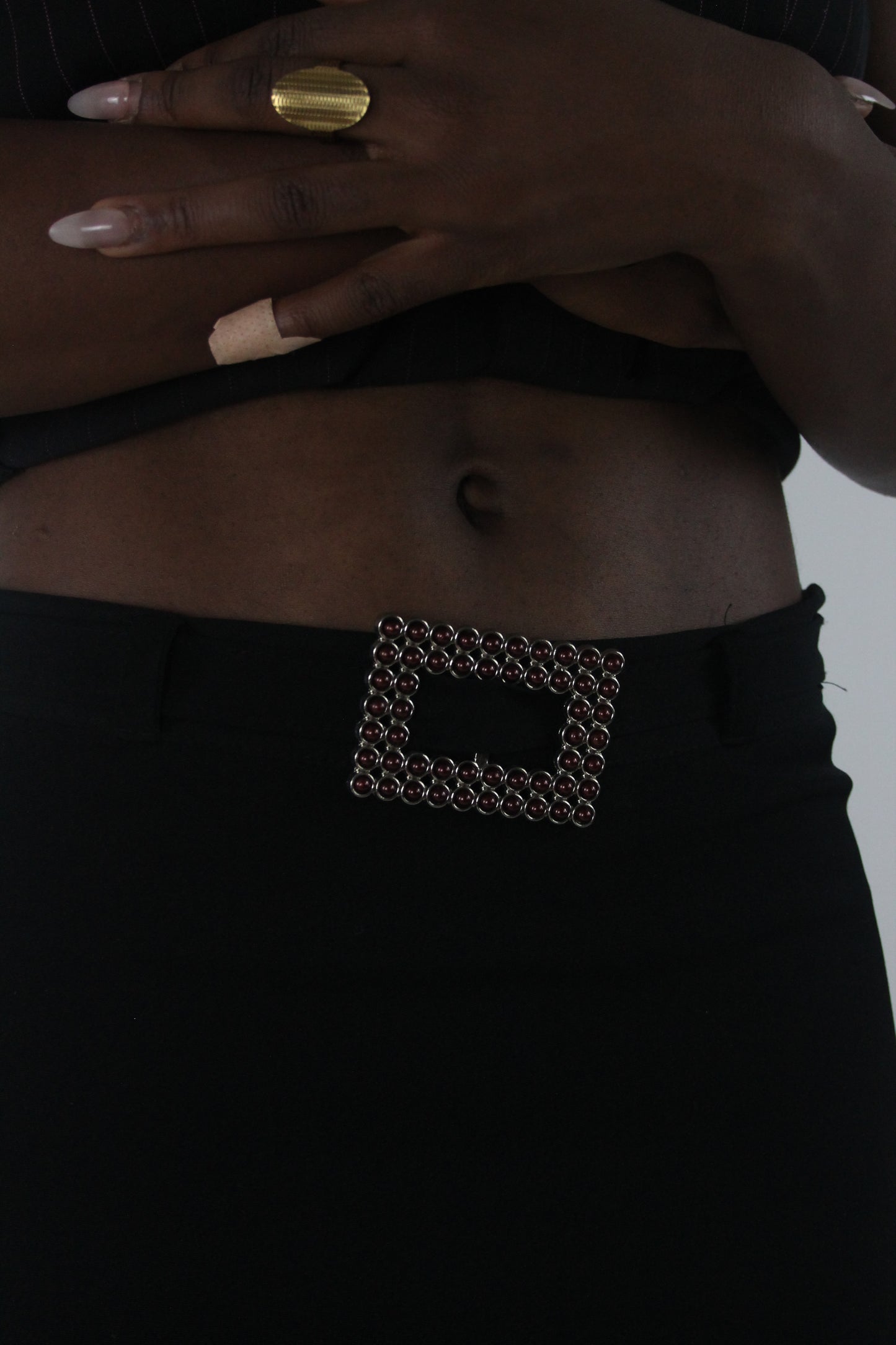 detail view of black rhinestone-buckle midi skirt