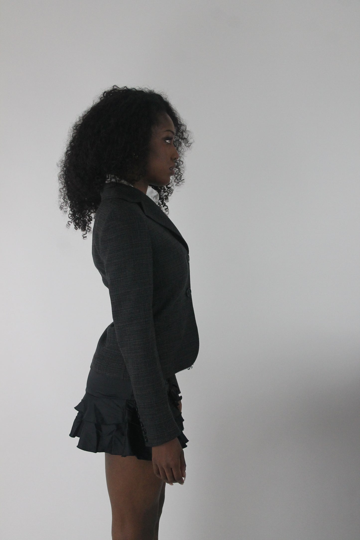 alternate-side view of charcoal grey ruffle-hem fitted blazer