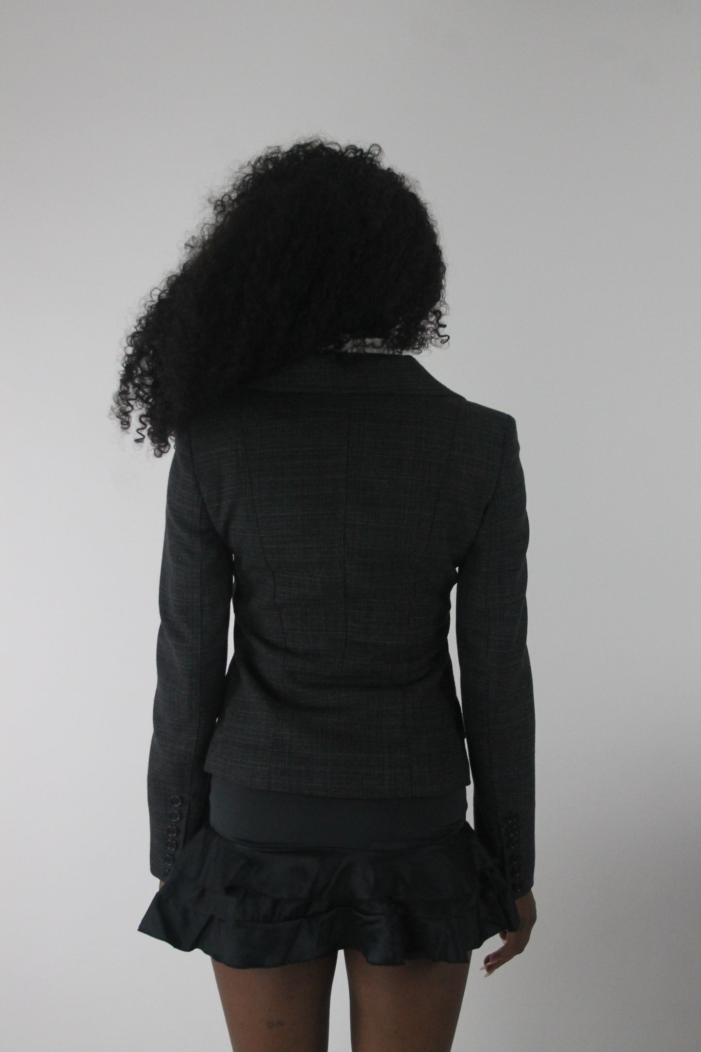 back view of charcoal grey ruffle-hem fitted blazer