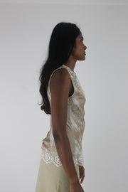 side view of small cream satin-effect sleeveless top with white lace trim