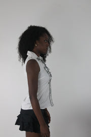 alternate-side view of white sleeveless collared shirt with black piping
