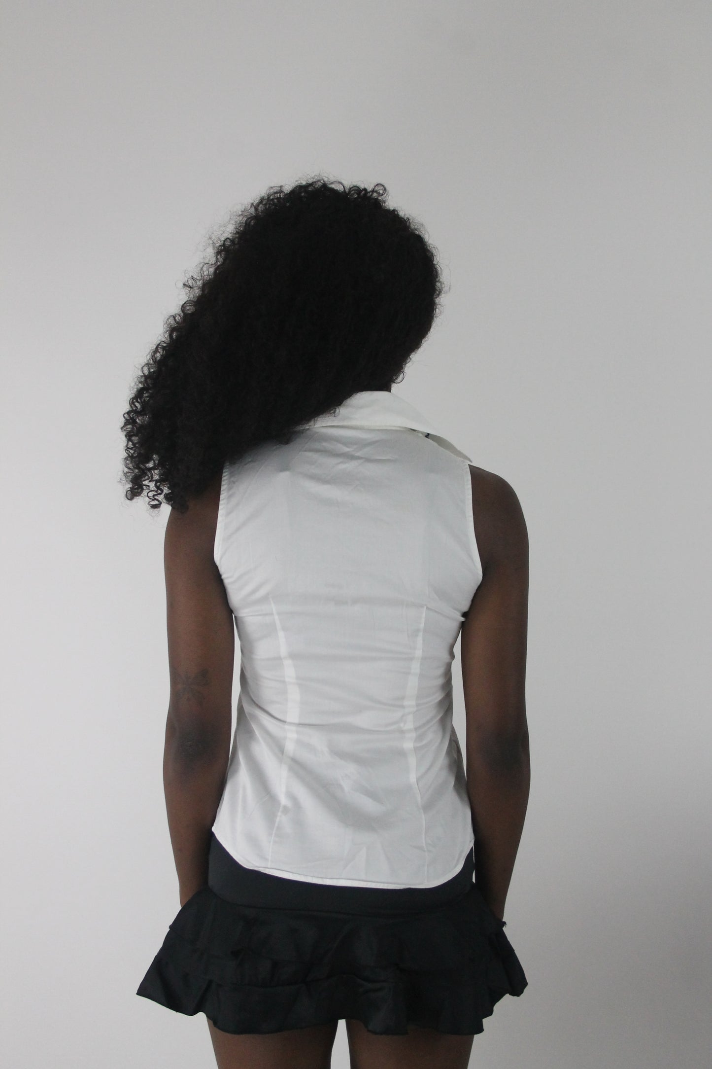 back view of white sleeveless collared shirt with black piping