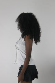 side view of white sleeveless collared shirt with black piping