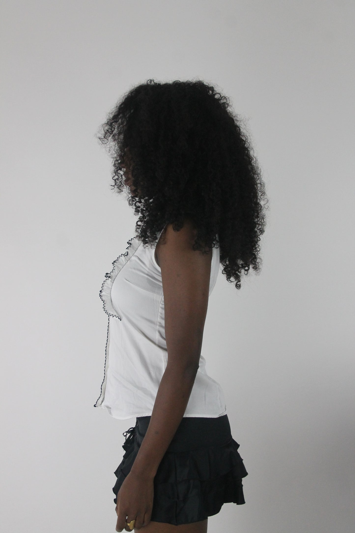 side view of white sleeveless collared shirt with black piping